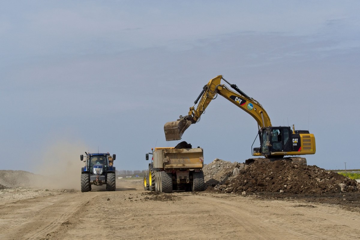Excavator loading construction and demolition debris into a dump truck on a job site