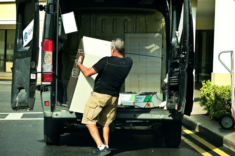 Worker loading a cabinet into the back of a van, similar to a junk removal pickup