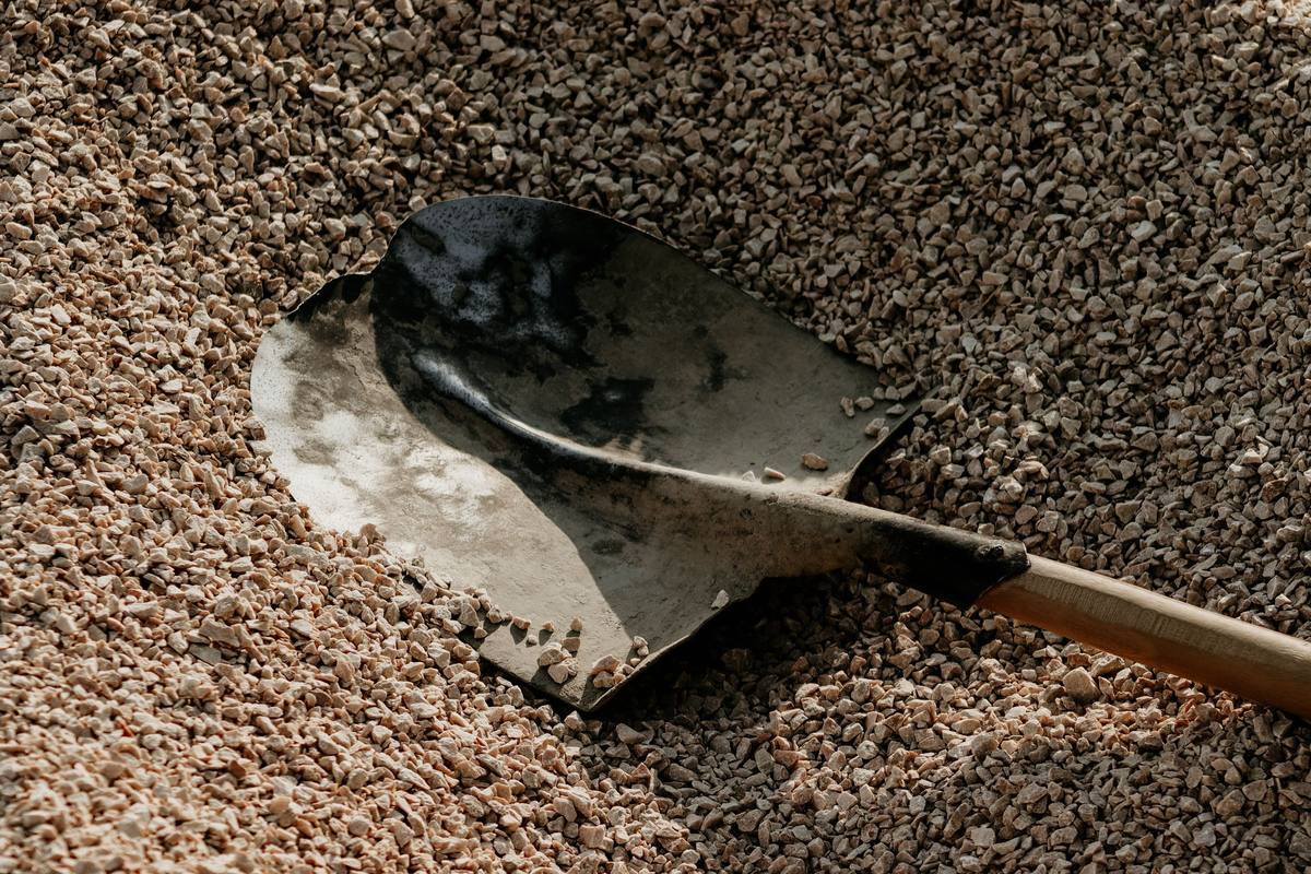 Shovel resting on a pile of gravel during a landscaping project